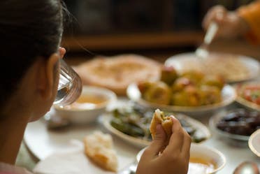 A young girl drinks water at the dinner table. (Stock image)