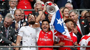 Arsenal's Chilean striker Alexis Sanchez lifts the FA Cup trophy as Arsenal players celebrate their victory over Chelsea in the English FA Cup final football match between Arsenal and Chelsea at Wembley stadium in London on May 27, 2017. (AFP)