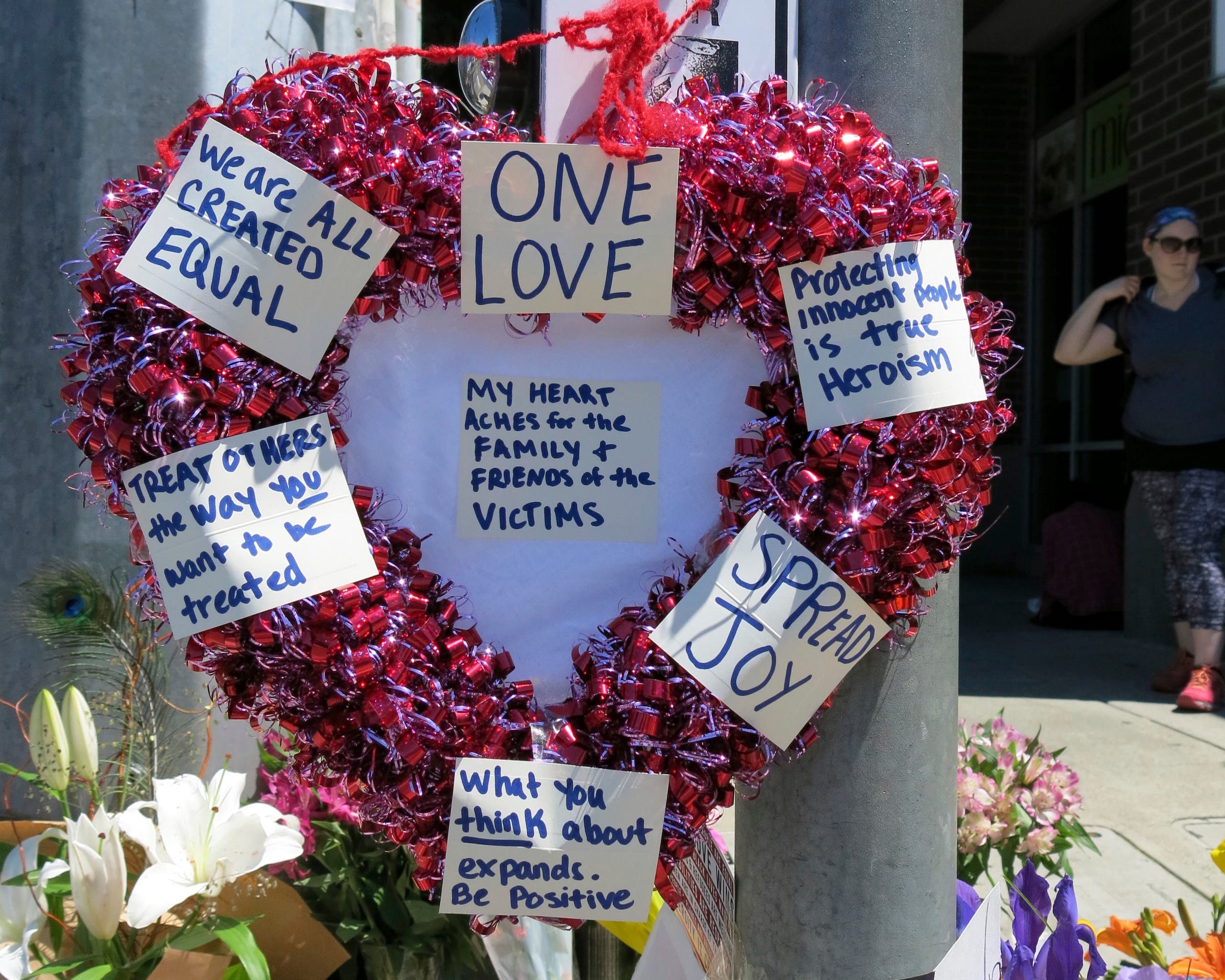 A heart-shaped wreath covered with positive messages hangs on a traffic light pole at a memorial for two bystanders who were stabbed to death Friday. (AP)