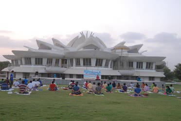 A unique lotus-shaped building with many people doing yoga on open ground. (Supplied)