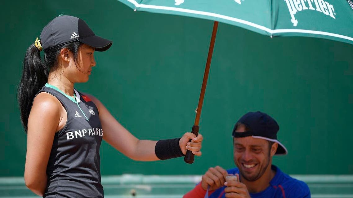 A ball girl holds an umbrella over Italy's Paolo Lorenzi as he rewraps his racket during his tennis match against US John Isner at the Roland Garros 2017 French Open on June 1, 2017 in Paris. (AFP)
