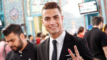 Iranian Reza Alireza Lou, a look-alike of Real Madrid's Portuguese soccer player Cristiano Ronaldo, holds his ID card as he poses for photographs during the Iranian presidential elections on May 19, 2017 at a polling station in Tehran.  (STR/AFP)