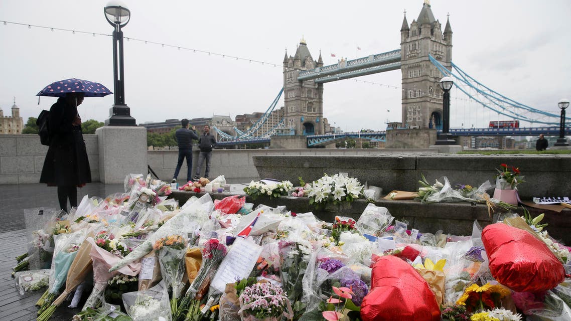 A woman at looks at flowers placed for attack victims at Potters Field Park in London, Tuesday, June 6, 2017. AP