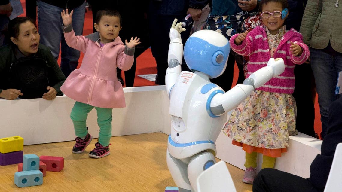 Children dance with a companion robot displayed at the World Robot Conference held in Beijing. (File photo: AP)