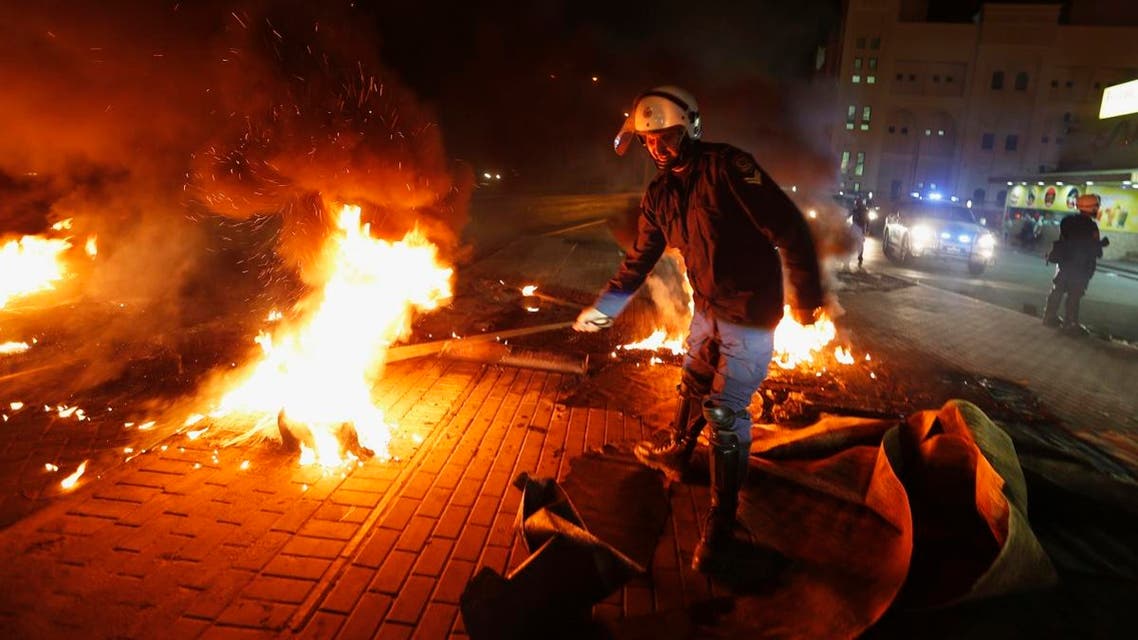 A riot police officer removes burning tyres from the highway set up by anti-government protesters in the village of Diraz west of Manama April 11, 2013. (Reuters)