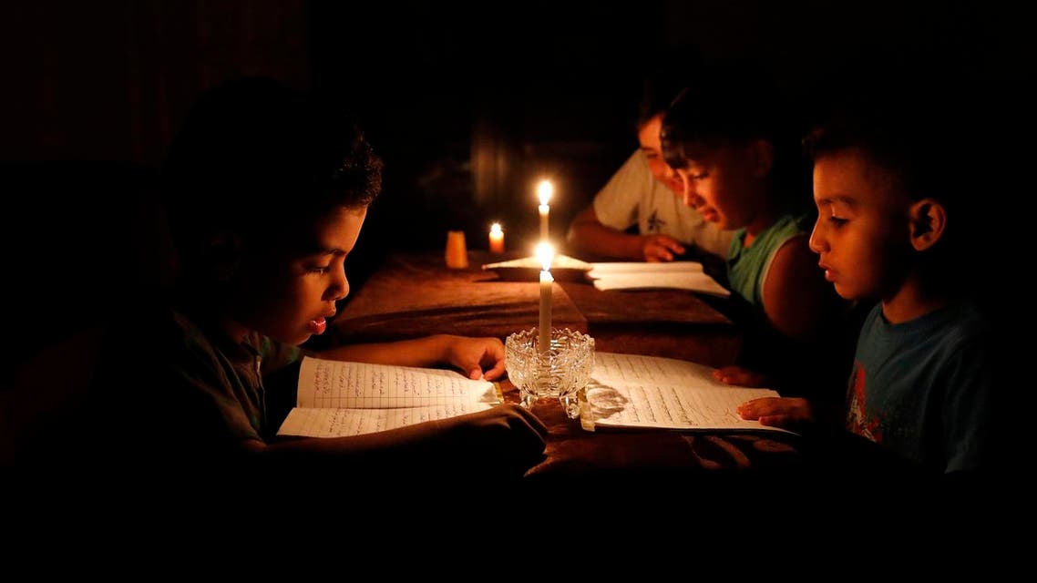 A picture taken on June 13, 2017, shows Palestinian children at home reading books by candle light due to electricity shortages in Gaza City. Israeli Prime Minister Benjamin Netanyahu said he was not seeking an "escalation" in the Gaza Strip after his government moved to reduce electricity supplies to the Hamas-run enclave. (afp)