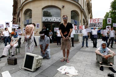 Activists from Reporters Without Borders (RSF) with fake injuries, tied hands and legs with chains, attend a demonstration on Champs Elysees Avenue in front of the Iran Air airline company in Paris July 10, 2012 to condemn the imprisonment of journalists and citizen journalists in Iran. reuters