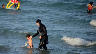 A Burkini-clad woman with a child take to the waters at the beach. (Supplied)