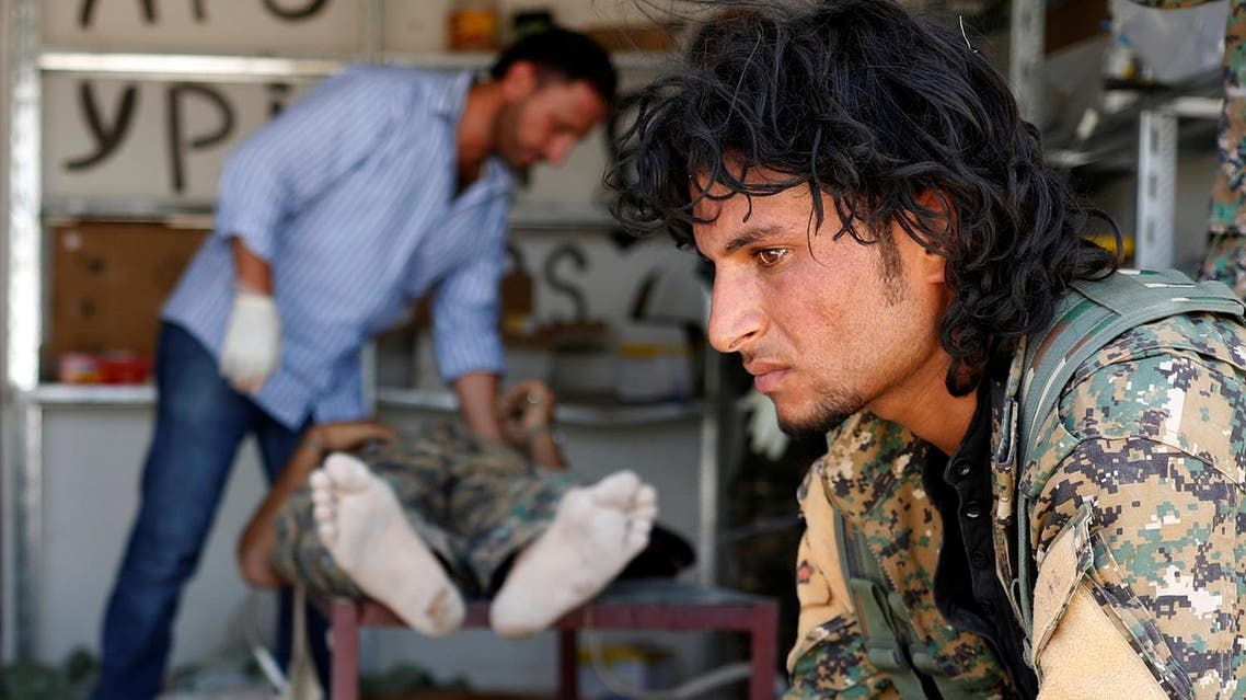 A Syrian Democratic Forces fighter sit as medics treat his comrades injured by sniper fired by ISIS militants in a field hospital in Raqqa, Syria June 28, 2017. (Reuters)