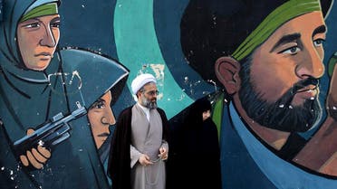 A cleric and his wife stand in front of a mural showing depicting members of paramilitary Basij during an annual pro-Palestinian rally marking Al-Quds Day in Tehran on June 23, 2017. (AP)