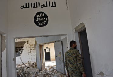 his file photo taken on March 30, 2017 shows a Syrian government forces fighter walking under Islamic State (IS) group graffiti in a house in Deir Hafer on the eastern outskirts of Aleppo on March 30, 2017. AFP