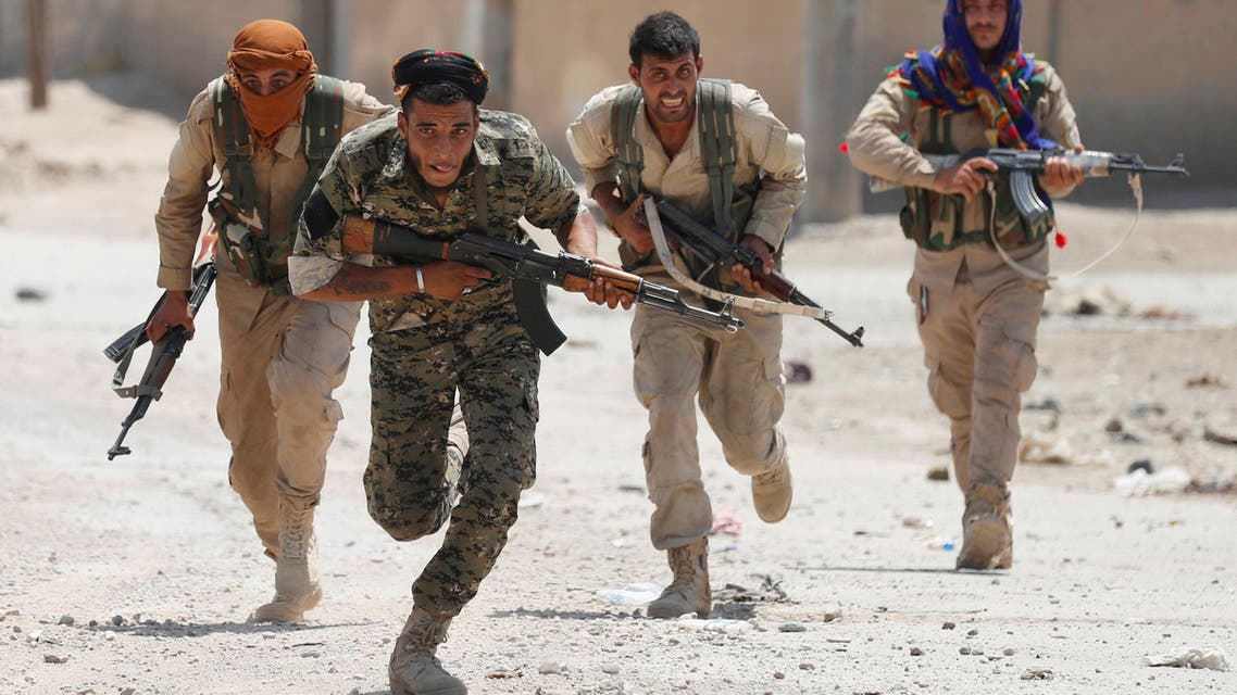 Kurdish fighters from the People's Protection Units (YPG) run across a street in Raqqa, Syria July 3, 2017