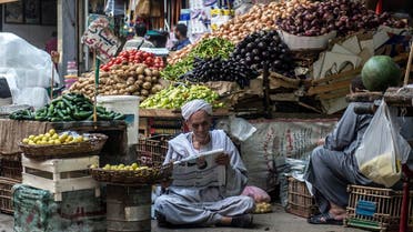 An Egyptian vendor reads the newspaper outside his fruit and vegetable stand in Egyptians in Cairo, on May 15, 2017. (AFP)