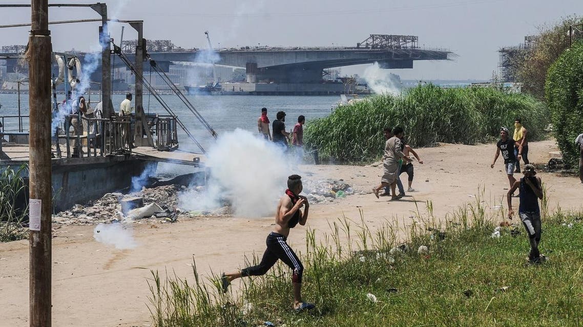 Egyptians run for cover from tear gas during clashes with security forces in the Nile island of Warraq in Giza province. (AFP)