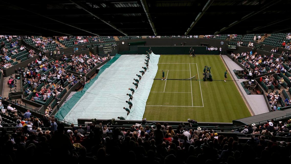 Ground staff pull the covers off following a rain delay at the All England Lawn Tennis Championships at Wimbledon, England, on June 26, 2012. (AP)