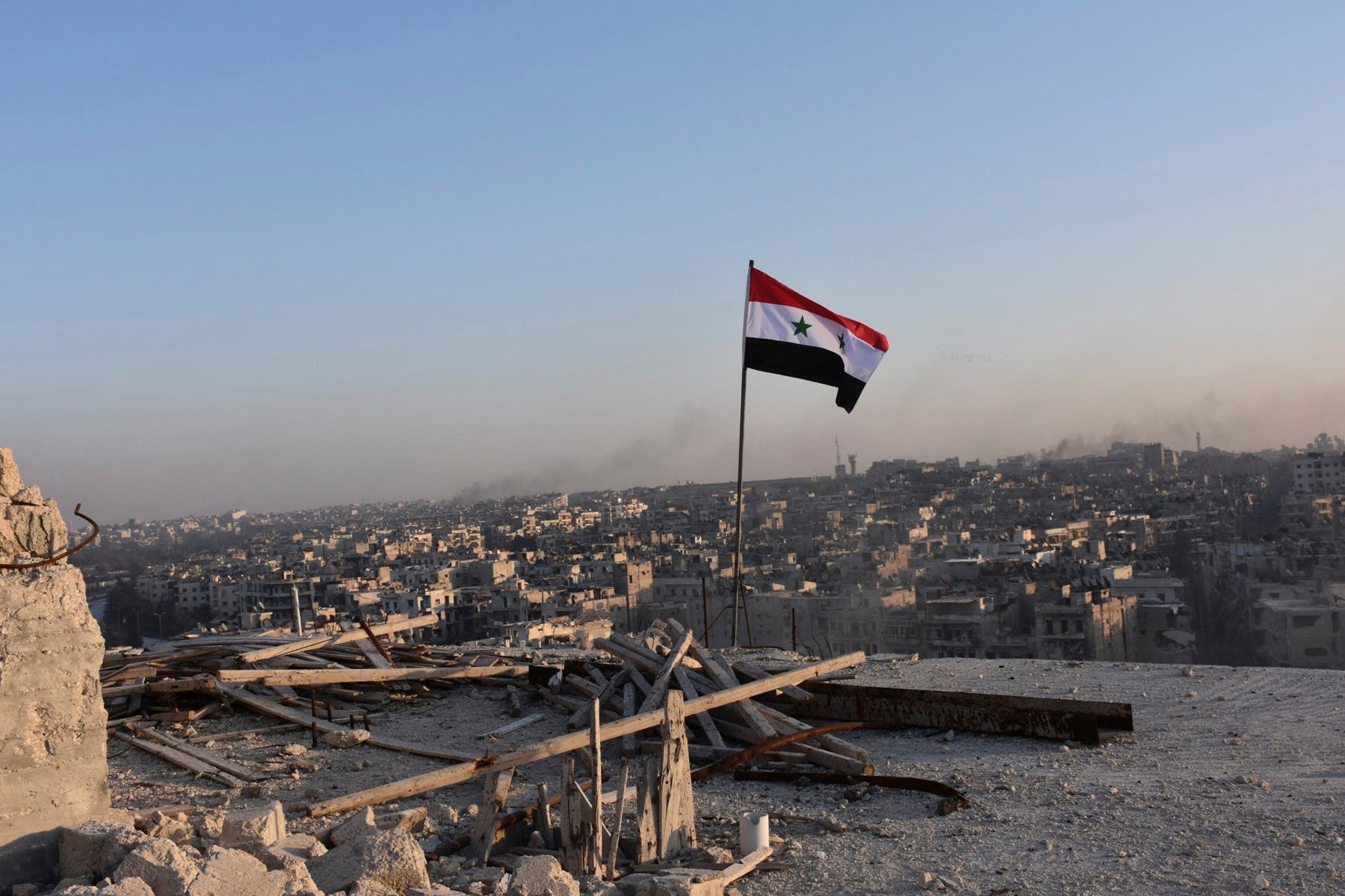 A Syrian national flag flutters near a general view of eastern Aleppo after Syrian government soldiers took control of al-Sakhour neigborhood in Aleppo. (Reuters)