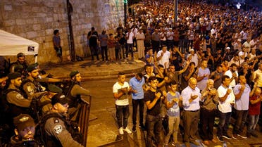 Israeli security forces stand by as Palestinian Muslim worshippers pray outside Lions' Gate, a main entrance to the Al-Aqsa mosque compound. (AFP)