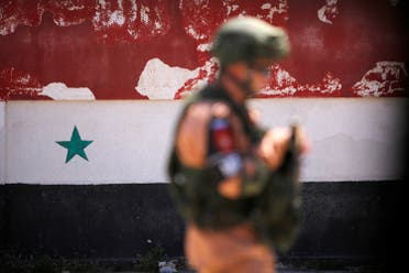 A Russian soldier stands guard near a Syrian national flag, Syria May 21, 2017. (Reuters)