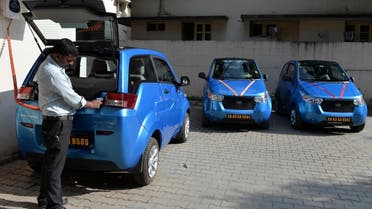 An employee of Indian company Carzonrent plugs in a Mahindra Reva electric car to charge in Bangalore on October 1, 2013. (AFP)