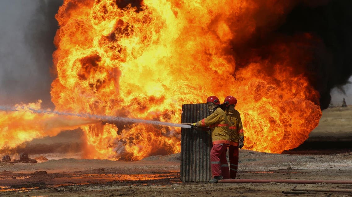 Oil workers and firemen try to extinguish flames at the Khabbaz oil field some 20 km away from Kirkuk on June 1, 2016 following an attack by ISIS. (AFP)