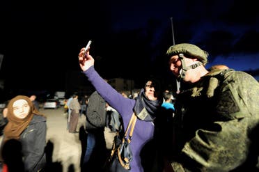 A Syrian woman takes a selfie with a Russian commander inside Waer district, after rebel fighters and their families evacuated the besieged district in the central Syrian city of Homs. (Reuters)