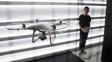 A employee (R) demonstrates an unmanned aerial vehicle (UAV or Drone) during the opening of the DJI flagship store in the Causeway Bay district of Hong Kong on September 24, 2016. DJI is a Chinese technology company founded in 2006 by Frank Wang and makes unmanned aerial vehicles (UVA or Drones) for aerial photography and videography.