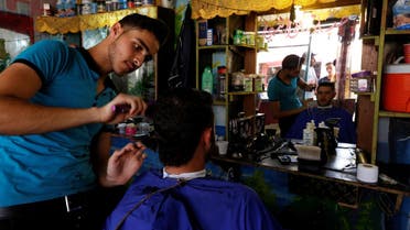 A Syrian barber gives a man a haircut at the main market in Al Zaatari refugee camp outside the city of Mafraq in Jordan. (File photo: Reuters)