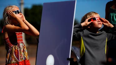 A reflected image of the sun is seen on a white board as kids look up to view the beginning a partial solar eclipse outside the Reuben H. Fleet Science Center in San Diego, California October 23, 2014. (Reuters)