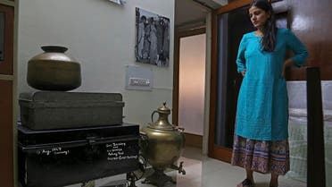 CEO of India’s new partition museum Mallika Ahluwalia looks at a steel trunk, black, which was among items donated by the relative of a person who had migrated to India in 1947. (AP)