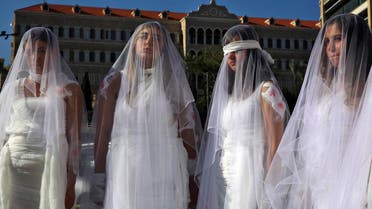 A dozen Lebanese women, dressed as brides in white wedding dresses stained with fake blood and bandaging their eyes, knees and hands stand in front of the government building in downtown Beirut, Lebanon, Tuesday, Dec. 6, 2016. (AP)