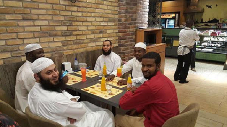 في المطعم قبل الهجوم، الدكتور العلي ملتفتا ينظر الى ملتقط الصورة، ومقابله الى اليسار الشيخ فهد الحسيني