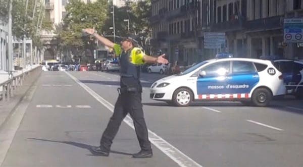 a police officer gesturing while walking across a road, after a van crashed into people in the centre of Barcelona, Spain, August 17, 2017. Reuters