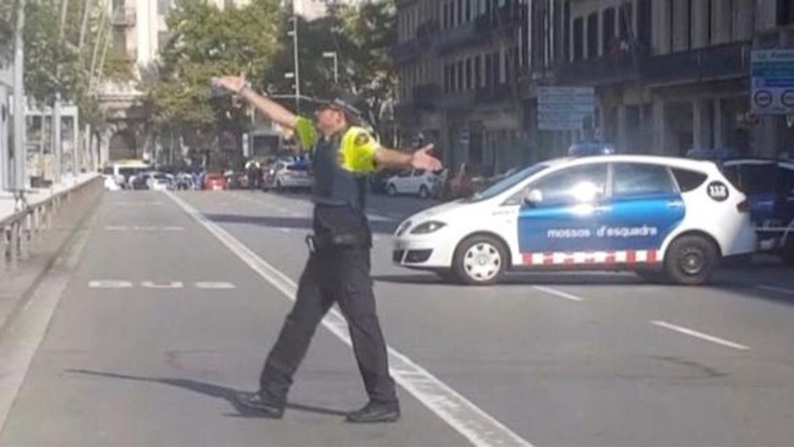 a police officer gesturing while walking across a road, after a van crashed into people in the centre of Barcelona, Spain, August 17, 2017. Reuters