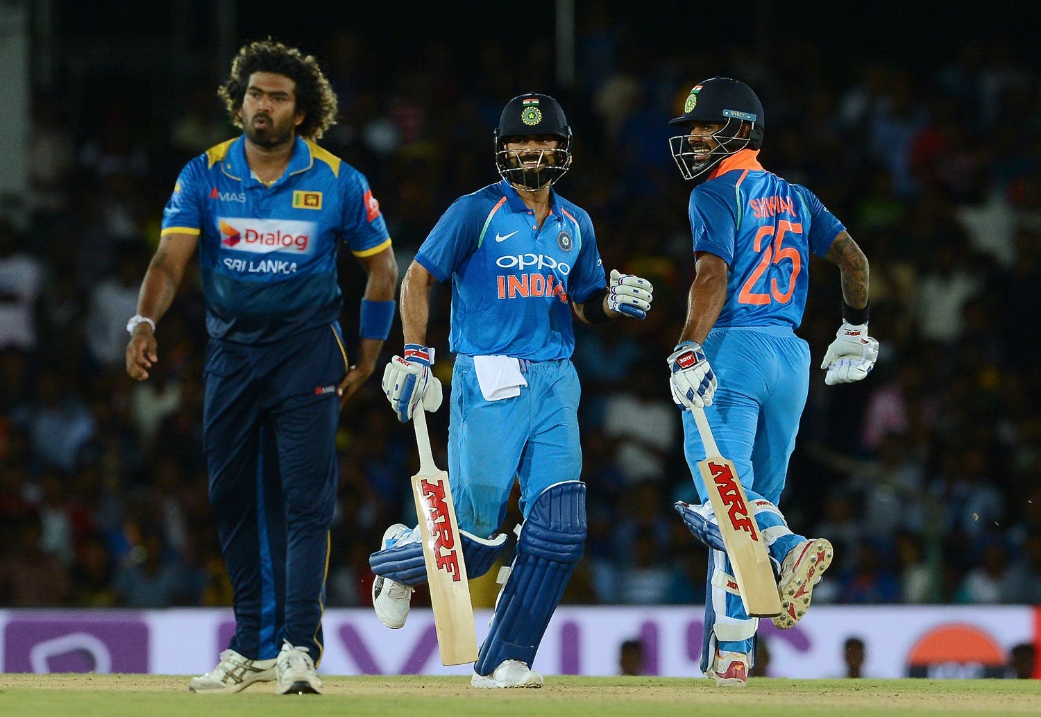 Indian cricket captain Virat Kohli (C) and Shikhar Dhawan run between the wickets during the first One Day International (ODI) cricket match between Sri Lanka and Indian at the Rangiri Dambulla International Cricket Stadium in Dambulla on August 20, 2017. AFP