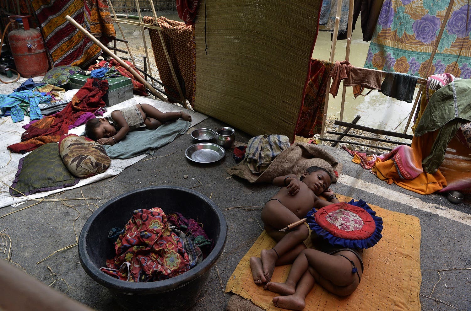 Indian children rest in a makeshift shelter at flood-affected Palsa village in Purnia district in Bihar state on August 18, 2017. At least 221 people have died and more than 1.5 million have been displaced by monsoon flooding across India, Nepal and Bangladesh, officials said August 15, as rescuers scoured submerged villages for the missing. (AFP)