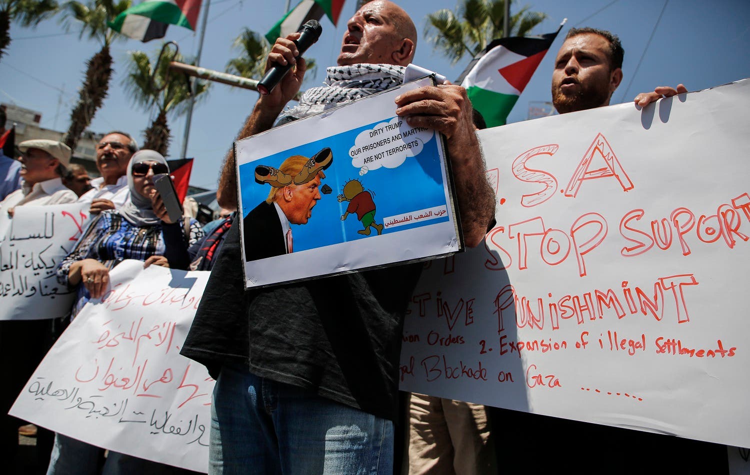 A picture taken on August 24, 2017 in the West Bank city of Ramallah shows Palestinian demonstrators holding a picture of US President Donald J. Trump defaced with cartoon shoes on his head along with other slogans, during a protest against the arrival of a US delegation headed by Jared Kushner. (AFP)