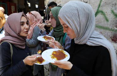 Women eat knafa outside al Aqsa sweet shop in the historic covered market of Nablus in the West Bank August 10, 2017. (File photo: Reuters)