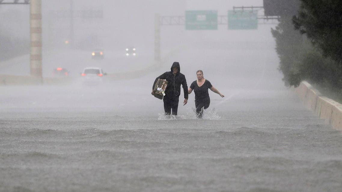 Two people walk down a flooded section of Interstate 610 in floodwaters from Tropical Storm Harvey on Sunday, Aug. 27, 2017, in Houston, Texas. (AP Photo/David J. Phillip)