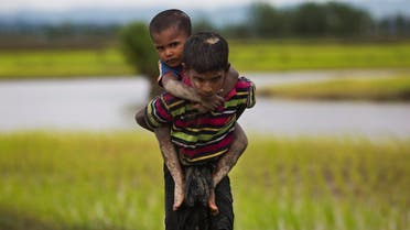 A Rohingya boy from Myanmar carries a child on his back and walks through rice fields after crossing over to the Bangladesh side on Sept. 1, 2017. (AP)