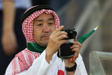A Japanese fan wears Saudi traditional clothes takes a picture. (AP)