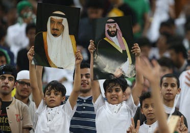 Saudi Arabia's fans hold up portraits of Saudi King Salman and Crown Prince Mohammed bin Salman during the FIFA World Cup 2018 qualification football match between Saudi and Japan at King Abdullah bin Abdulaziz Stadium in Jeddah on September 5, 2017. (AFP)
