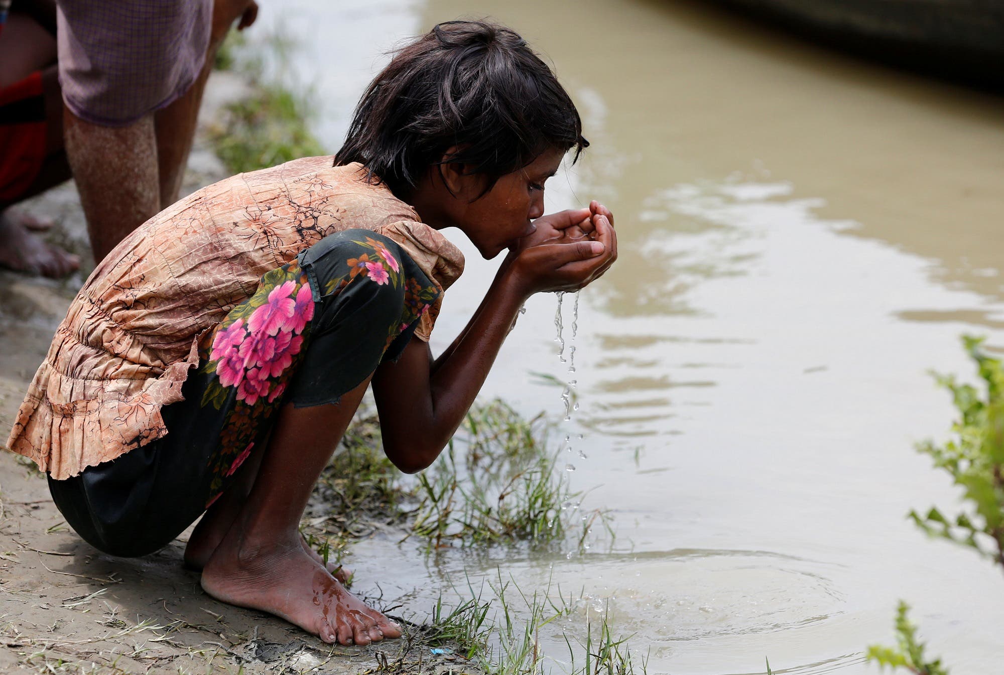 A Rohingya refugee girl drinks river water as she waits for boat to cross the border through Naf river in Maungdaw, Myanmar, September 7, 2017. (Reuters)
