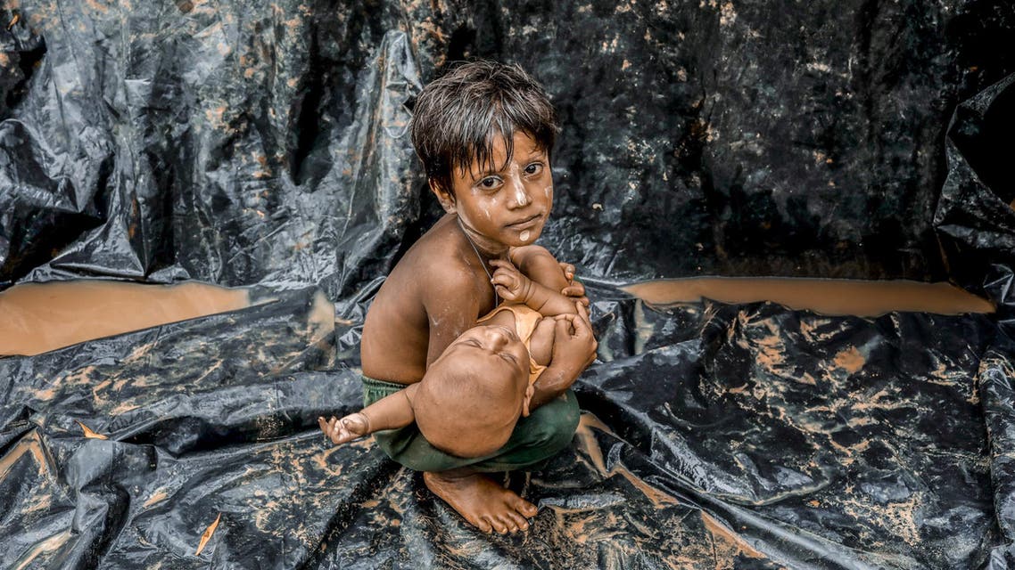 A Rohingya refugee from Myanmar's Rakhine state holds a baby after arriving at a refugee camp near the Bangladeshi town of Teknaf on September 5, 2017.