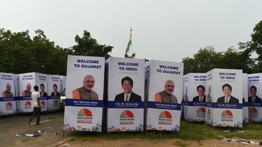 An Indian worker walks past poster with the picture of Japanese Prime Minister Shinzo Abe and his Indian counterpart Narendra Modi, in Ahmedabad on September 10, 2017. (AFP)