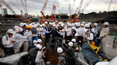 Japan's Tokyo Olympic minister Shunichi Suzuki, center, answer for reporter's question after inspect of a construction site of new national stadium in Tokyo, Tuesday, Sept. 12, 2017. Tokyo's main Olympic stadium is starting to take shape as structures of what will become spectator stands are being installed after 10 months of underground foundation work. (AP Photo/Shizuo Kambayashi)