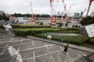 A Japanese man plays basketball at the Tokyo metropolitan gymnasium as the construction site for the National Stadium, venue for the upcoming Tokyo 2020 Olympics, is seen in the background in Tokyo on June 30, 2017. The International Olympic Committee (IOC) insisted on June 30 the showpiece venue for the Tokyo 2020 Summer Games would be completed on schedule after a disastrous rollout of the initial plans. (AFP)