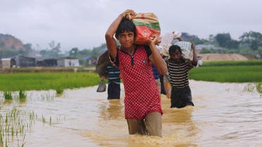 Rohingya refugees carry their belongings as they walk through a flooded pathway at a camp in Cox’s Bazar, Bangladesh, September 19, 2017. (Reuters)