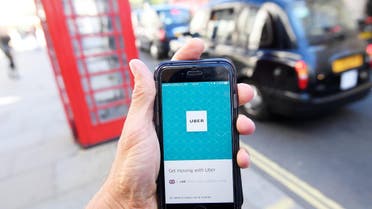 A photo illustration shows a London taxi passing as the Uber app logo is displayed on a mobile telephone in central London September 22, 2017. (Reuters)