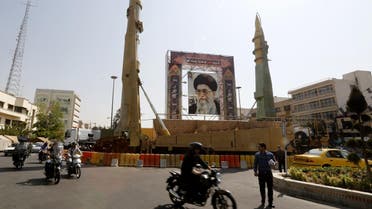 Iranians walk past Sejjil (L) and Qadr-H medium range ballistic missiles next to a portrait of Ayatollah Ali Khamenei on Baharestan square in Tehran on September 25, 2017. (AFP)
