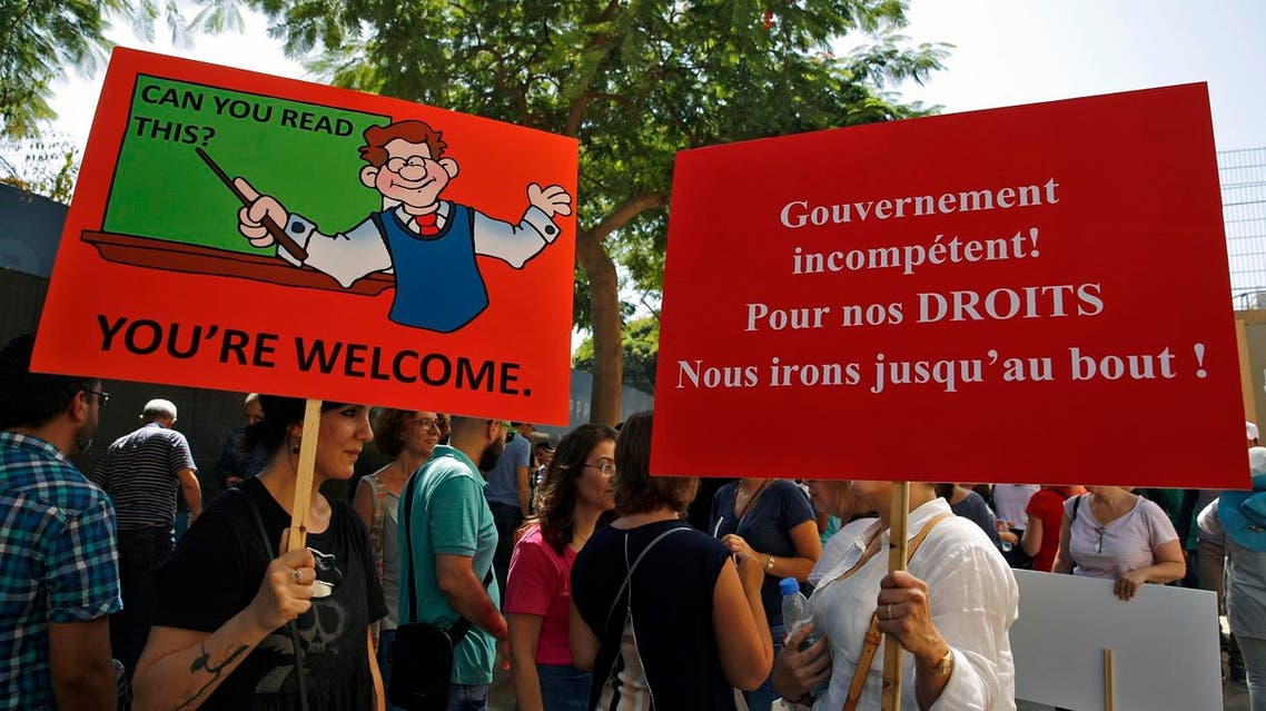 Public sector employees hold placards during a protest in front of the government building in downtown Beirut, Lebanon, Tuesday, Sept. 26, 2017. Lebanon's civil servants are on strike to pressure the government to pay them recently approved wage hikes amid a new crisis over how to finance the wages bill, estimated at $800 million. (AP Photo/Bilal Hussein)
